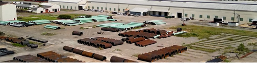Aerial view of an industrial yard with stacked pipes and containers
