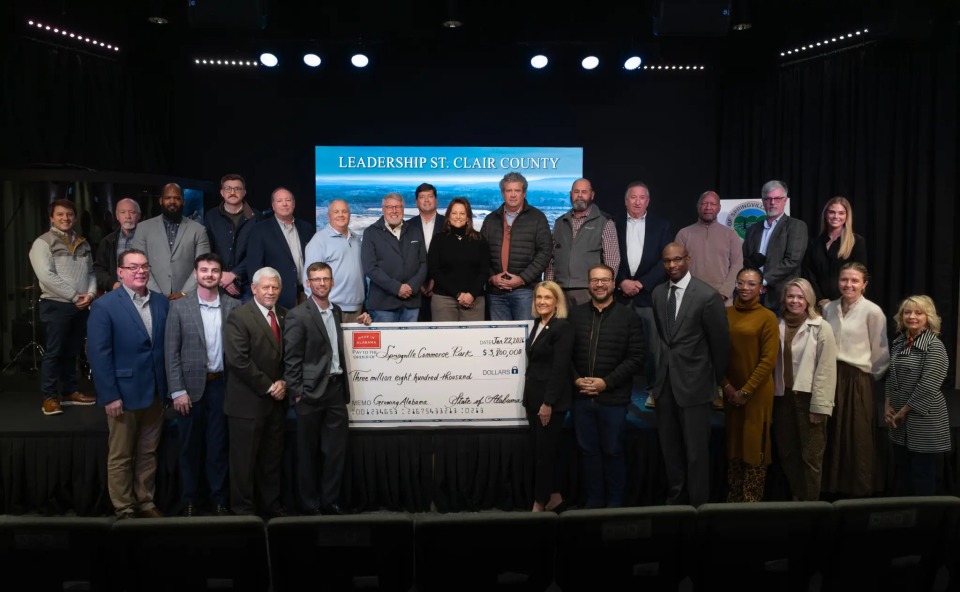A group of people posing with a large check for community funding