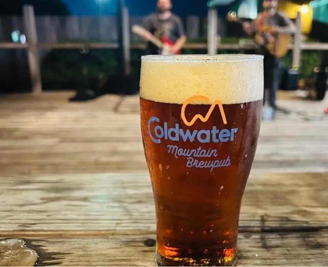 A chilled pint glass of Coldwater brew on a wooden table